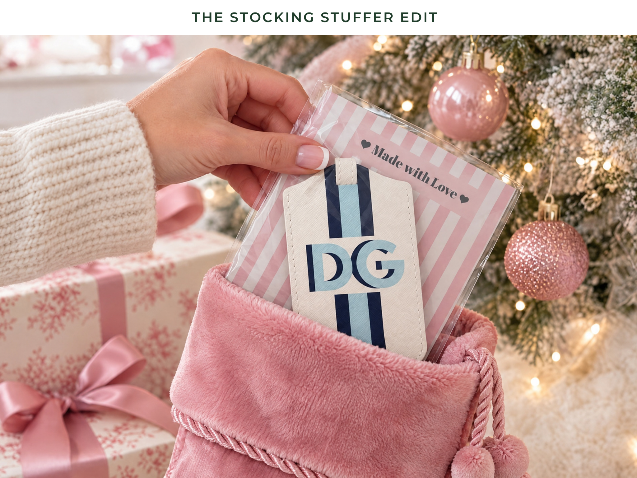 The Stocking Stuffer Edit: personalized luggage tag in a pink Christmas stocking next to holiday gifts and a Christmas tree